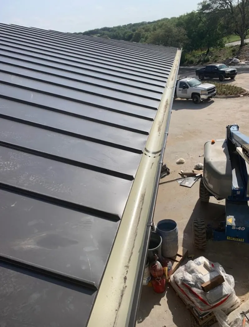 Standing seam panel and gutter detail on a metal roofing jobsite in Bow